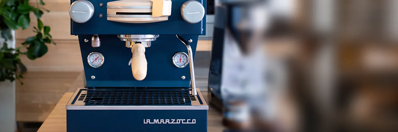 La Marzocco Home: a navy blue La Marzocco home espresso machine on a wooden kitchen bench.